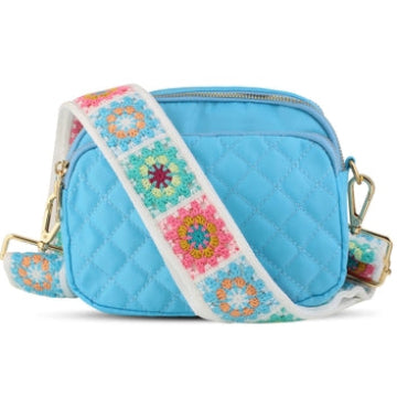 Blue quilted bag with a colorful floral strap on a white background