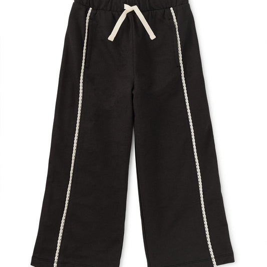 Black track pants with white lace trim on the legs and a drawstring waist.