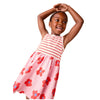 Young girl wearing a pink dress with red floral patterns on a beige background