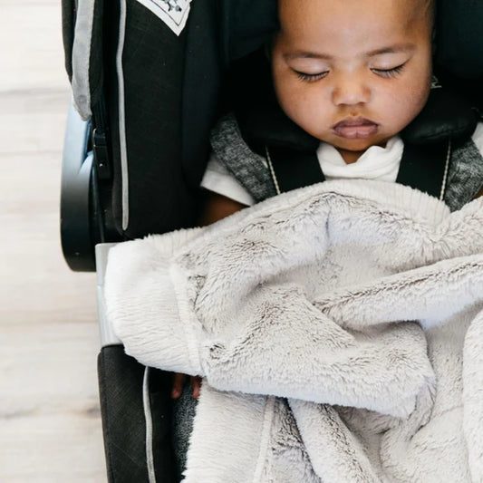 Child in a car seat wrapped in a gray blanket
