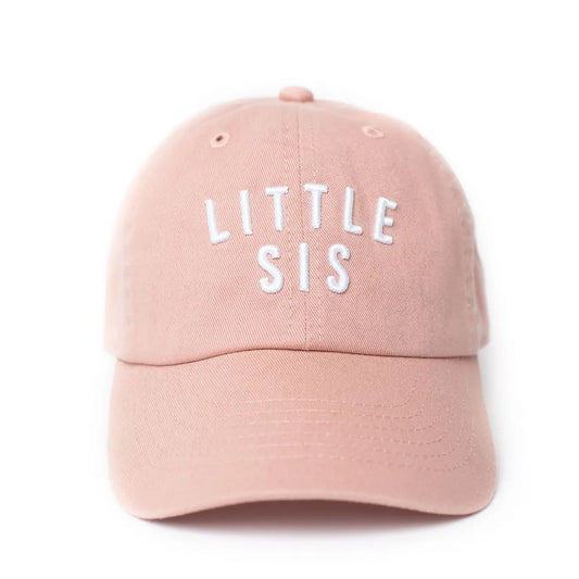 A pink hat with 'LITTLE SIS' written in white letters on the front.