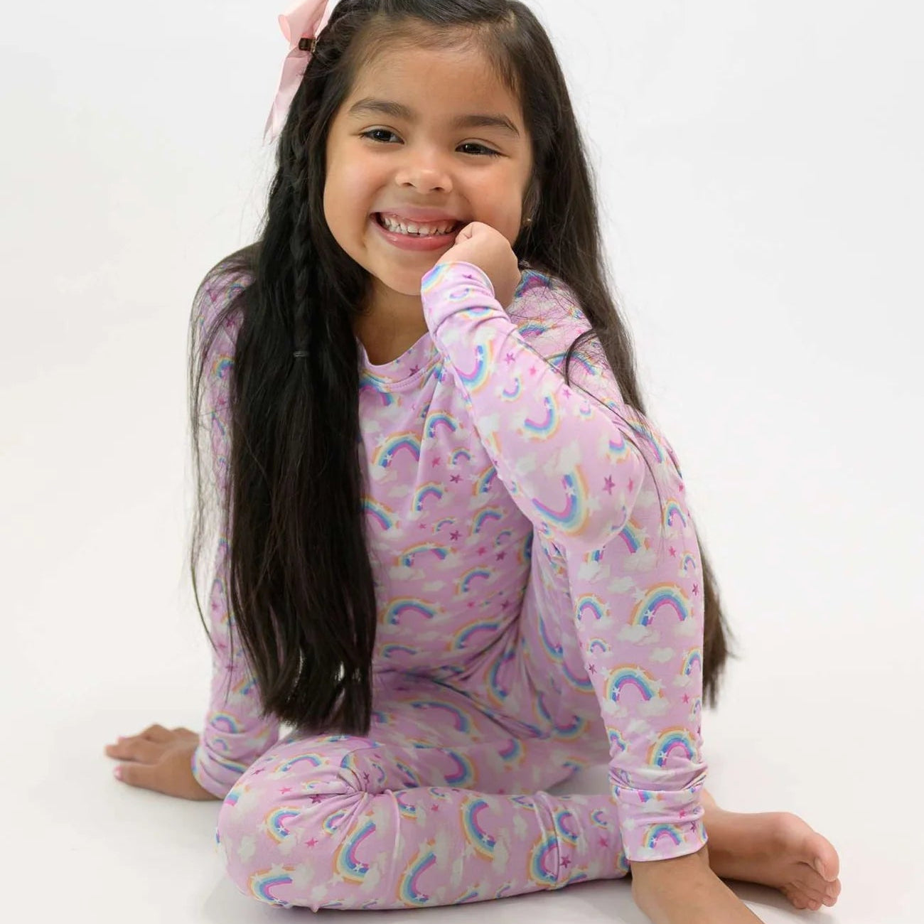 Young girl wearing a pink rainbow-themed outfit on a white background