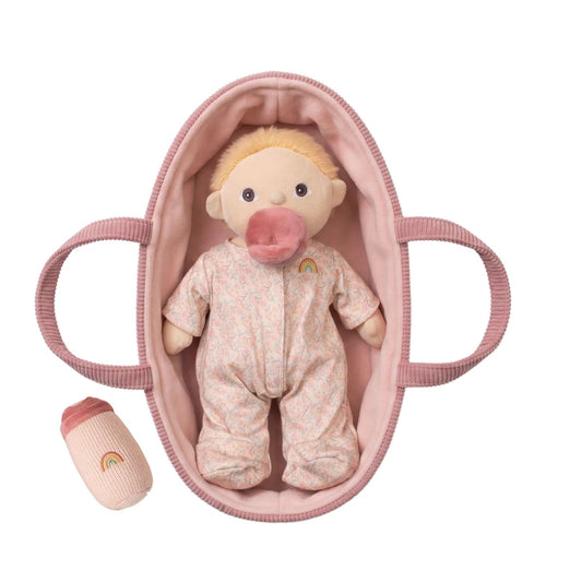 Baby doll in a pink crib with a pacifier on a white background