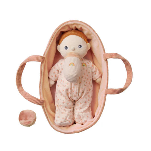 Baby doll with a pacifier and blanket in a pink crib