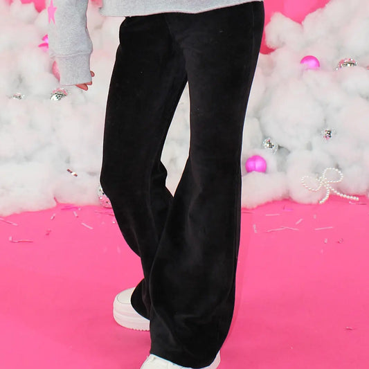 Person wearing a gray sweatshirt with text and black pants on a pink background