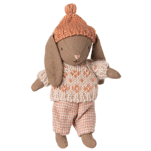 Stuffed rabbit toy wearing a knitted hat and sweater on a white background