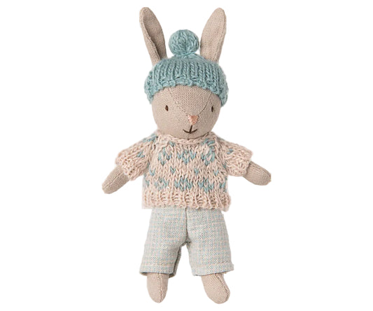 Toy rabbit wearing a knitted sweater and hat on a white background