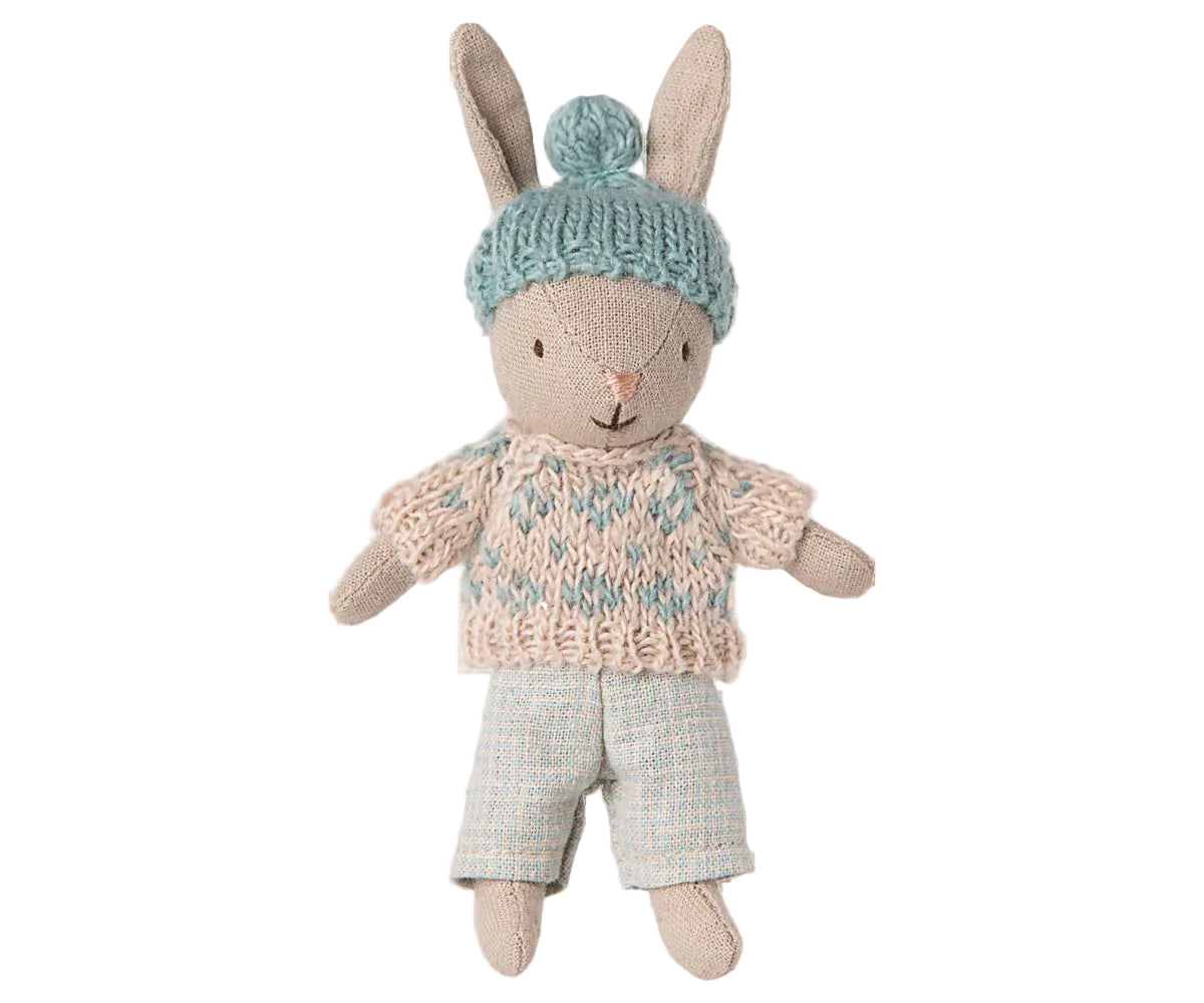 Toy rabbit wearing a knitted sweater and hat on a white background