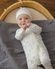Baby wearing the Cloud Floral Bamboo Zip Footie, lifestyle photo