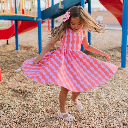 Child in a pink and white checkered dress at a playground
