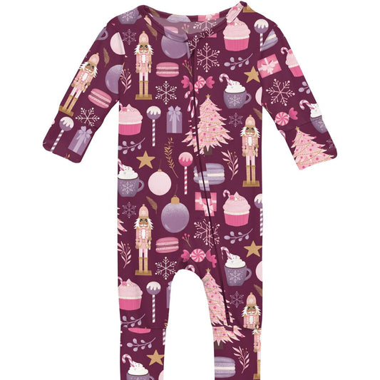A festive purple baby romper with flip paws and footies, featuring holiday-themed prints such as a nutcracker, candy cane, and snowflakes.