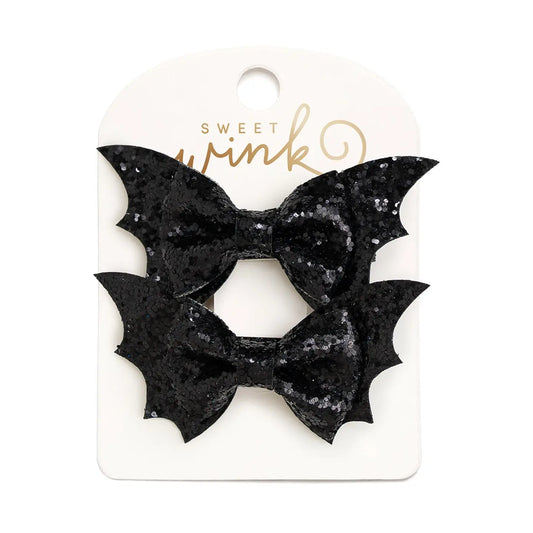 Two black sequined bat-wing shaped hair bows attached to a white Sweet Wink card, photographed on a white background.
