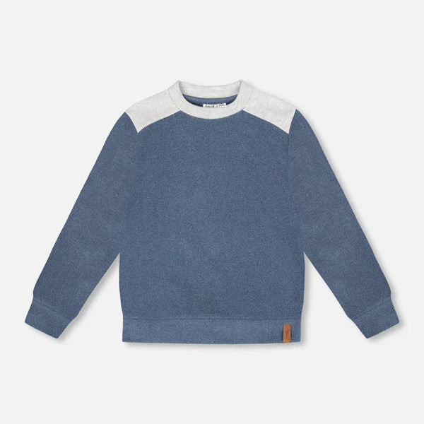 Blue sweater with white sleeves on a light gray background