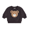 Black sweater with a bear face design on a beige background