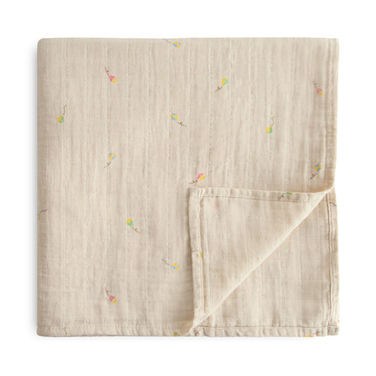 A swaddle blanket with a kite pattern on a light background, folded with one corner flipped over.