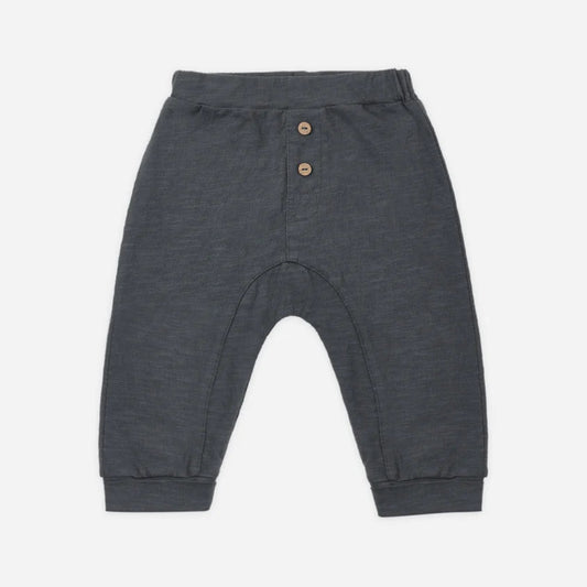Dark gray heathered knit pants for babies, featuring a buttoned henley waistband with two small wooden buttons, elastic cuffs, and a curved leg design, shown flat on a light gray background.