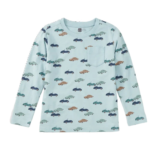 A light blue long-sleeve children's top with an allover pattern of small cars in navy, teal, and brown, featuring a left chest pocket.