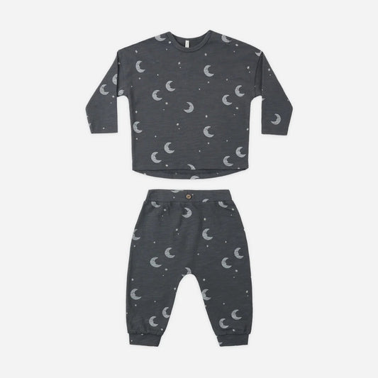 A two-piece children's pajama set in dark gray with a white crescent moon and star pattern, consisting of a long-sleeve top and matching pants, laid flat on a white background.