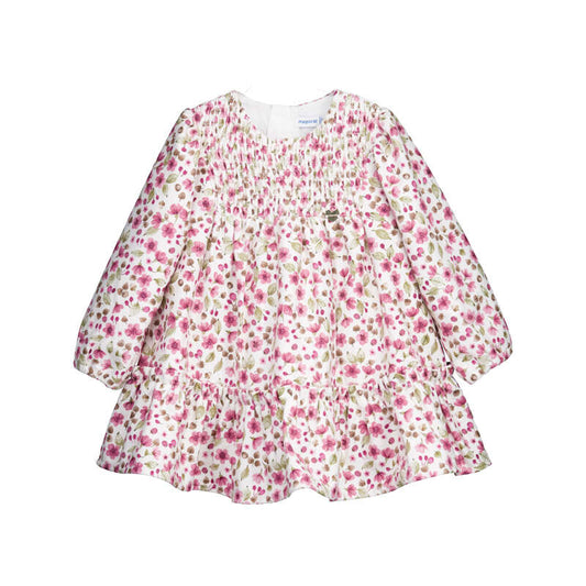 A long-sleeve baby dress with a pink and green floral print on a white background, featuring a smocked bodice and ruffled tiers.