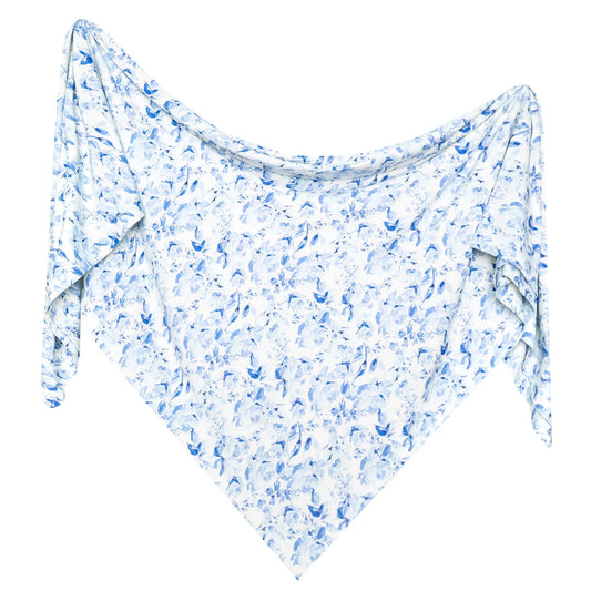 A lightweight white shawl or scarf with an all-over blue watercolor floral pattern, draped to show its triangular shape and flowing edges against a plain white background.