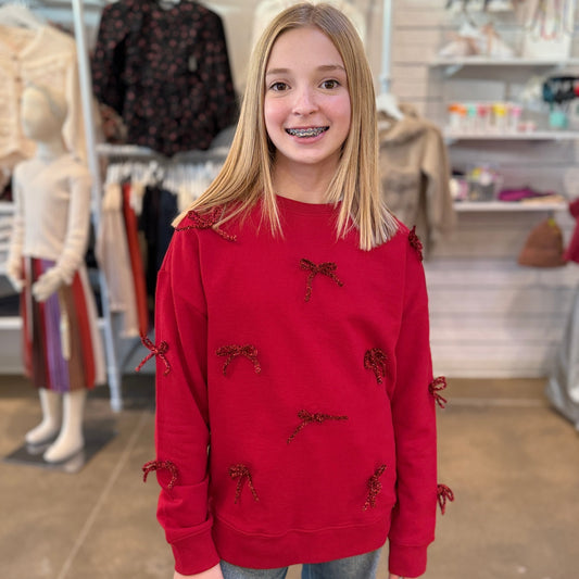 Young girl wearing a red sweater with bow details