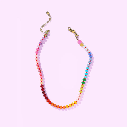 Colorful beaded necklace on a light pink background