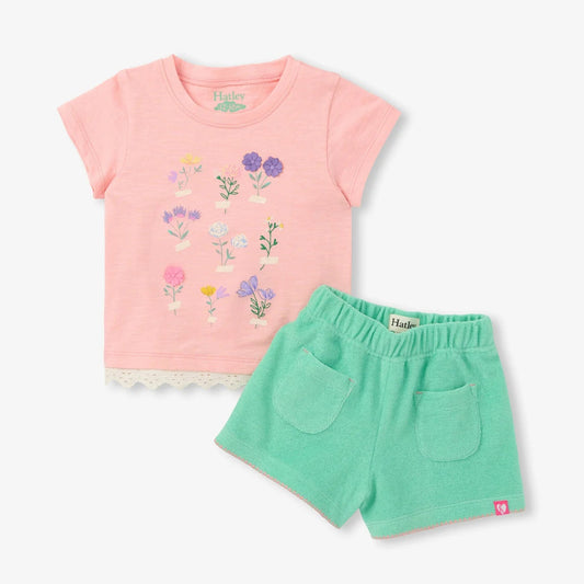 Children's outfit with pink floral t-shirt and green shorts on a white background