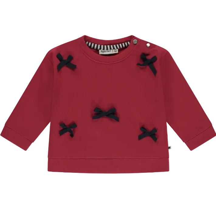 A red sweatshirt with petite grosgrain bows on it, designed for baby girls.