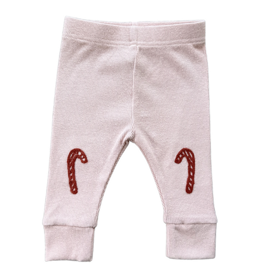 Baby leggings with candy cane designs on a white background