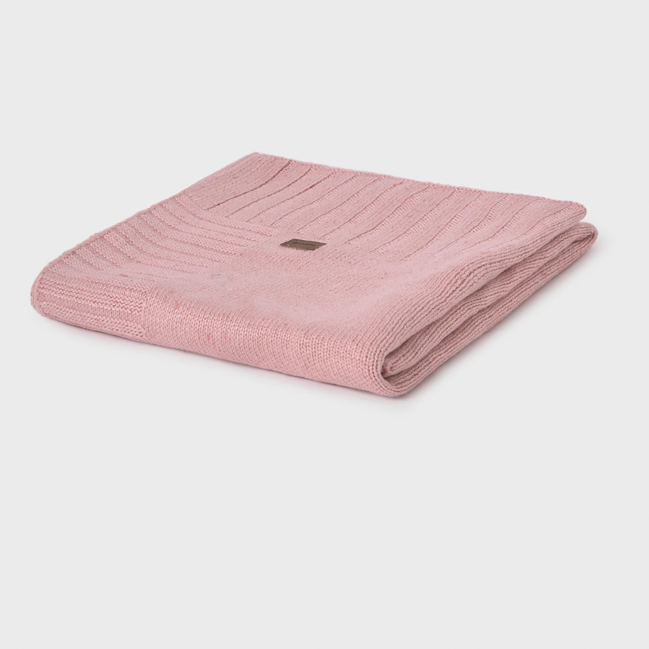 Folded pink knitted blanket on a light gray background