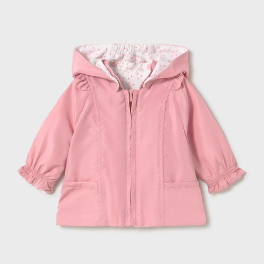 Pink reversible baby coat with dotted lining on a light gray background