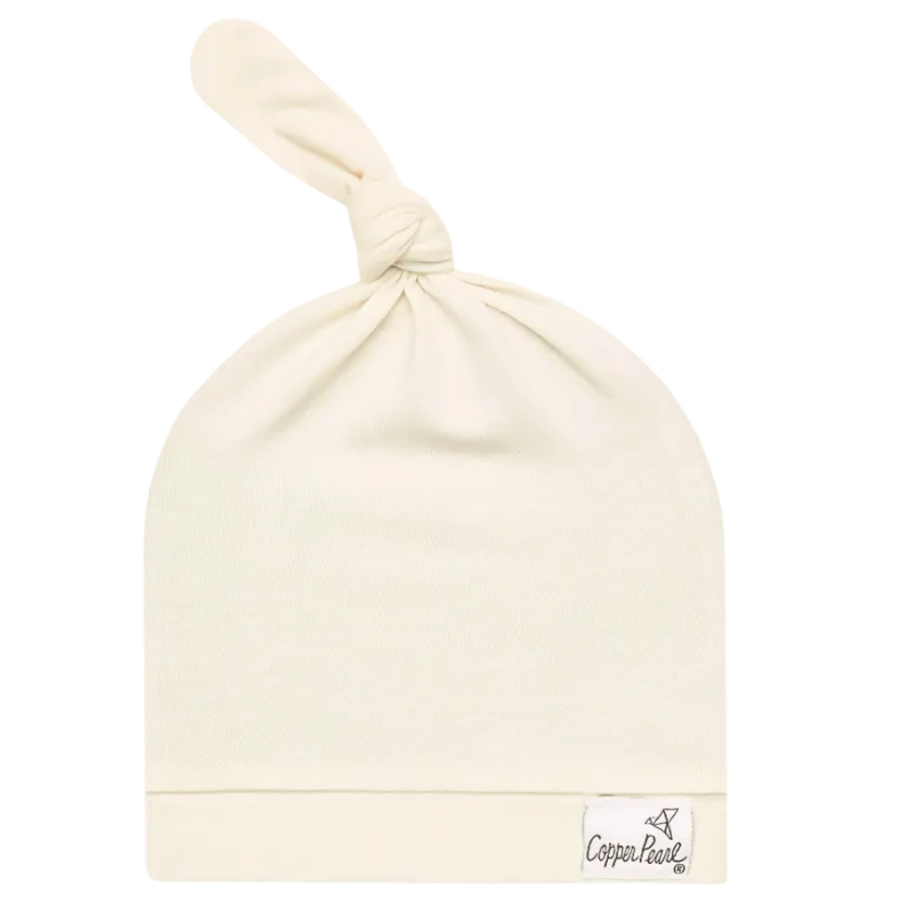 Beige baby hat with a knot on top on a white background, featuring the Copper Pearl brand.