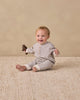 Baby wearing the Slate Stripe Henley Jumpsuit by Quincy Mae