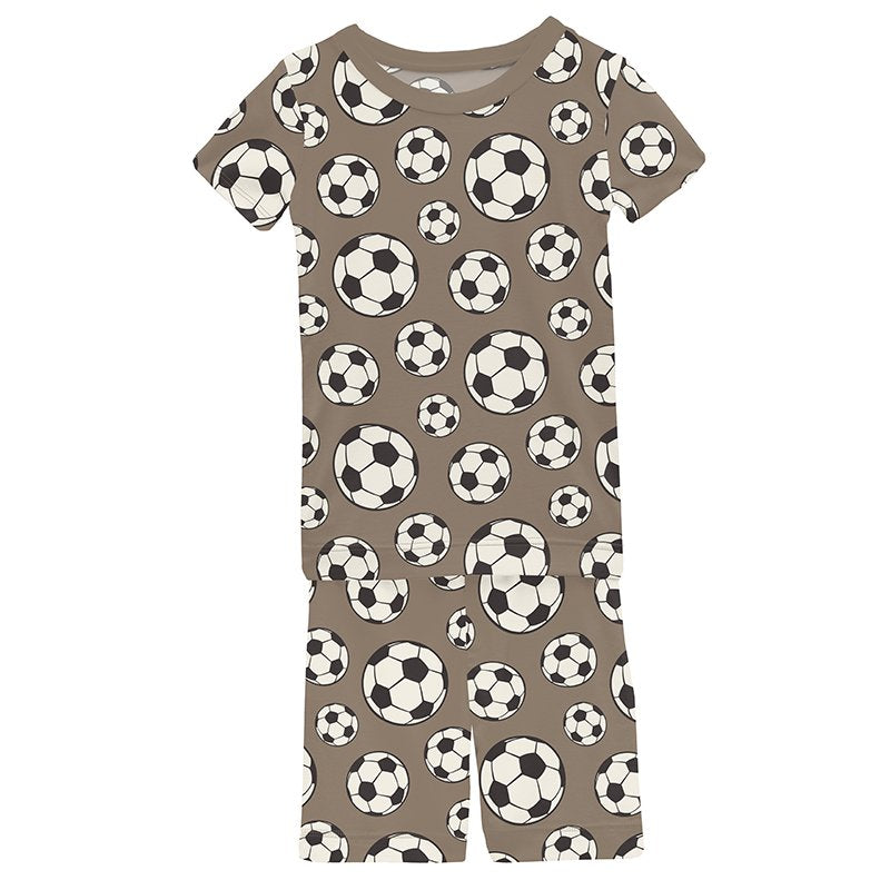 Boys short sleeve pajama set with soccer ball pattern on a brown background.