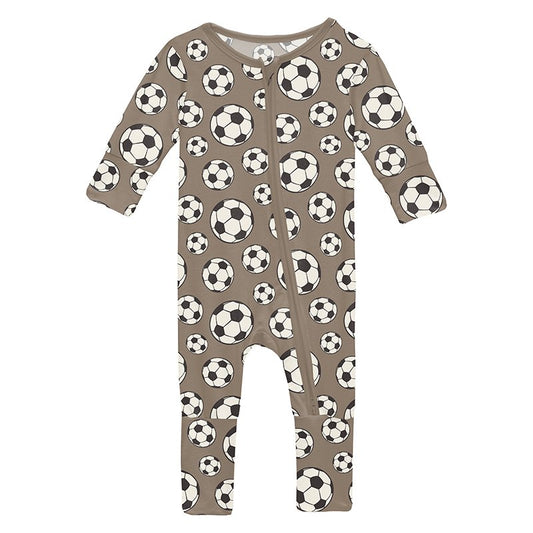 Baby zip footie with soccer ball pattern on a brown background