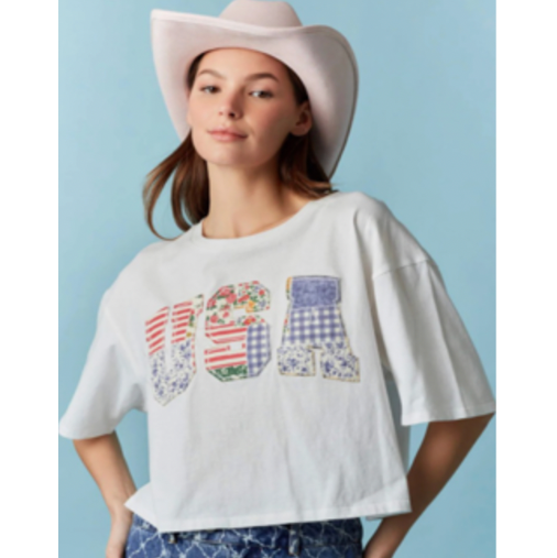 Woman wearing a white t-shirt with colorful 'USA' design and a pink cowboy hat on a light blue background