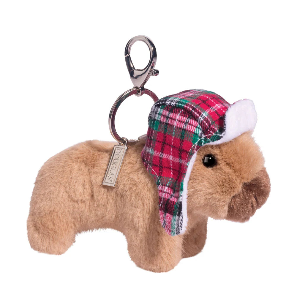 A small plush capybara keychain in tan fur wearing a red, green, and pink plaid winter hat with white trim, attached to a silver metal clasp on a white background.