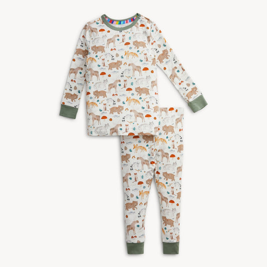 A two-piece children's pajama set featuring a long-sleeve top and matching pants with an all-over woodland animal print on an off-white background. The set has sage green cuffs and hem, and a small rainbow pattern on the inner collar.