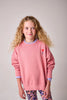Young girl wearing a pink sweatshirt with a small graphic