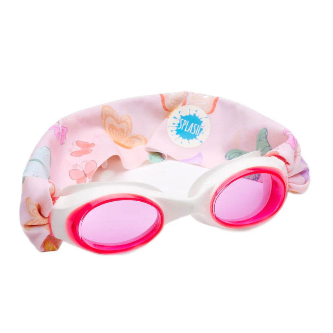 A pair of swim goggles with a tangle-free strap featuring a butterfly pattern on a light pink and peach background, and white frames with pink lenses.