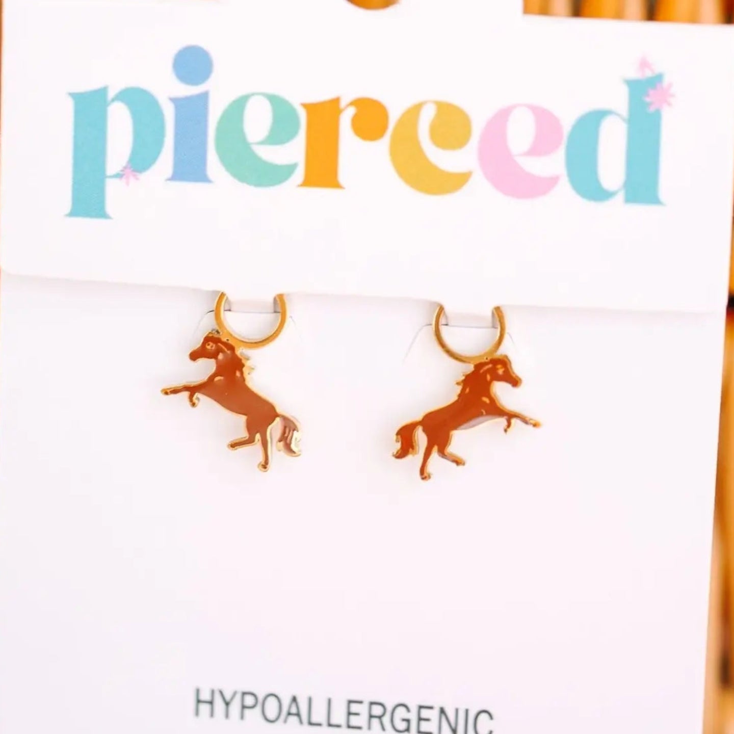 horse-shaped earrings on a 'pierced' branded card