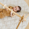 Baby lying on a quilted play mat with wooden toys
