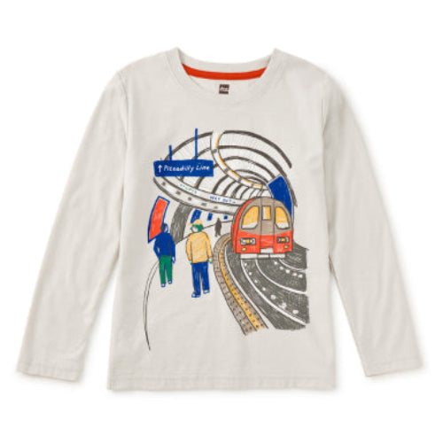 A long-sleeve crewneck t-shirt in off-white, featuring a colorful graphic print of a subway train station scene with a red train, platform workers, and a blue 'Premierly Line' sign.