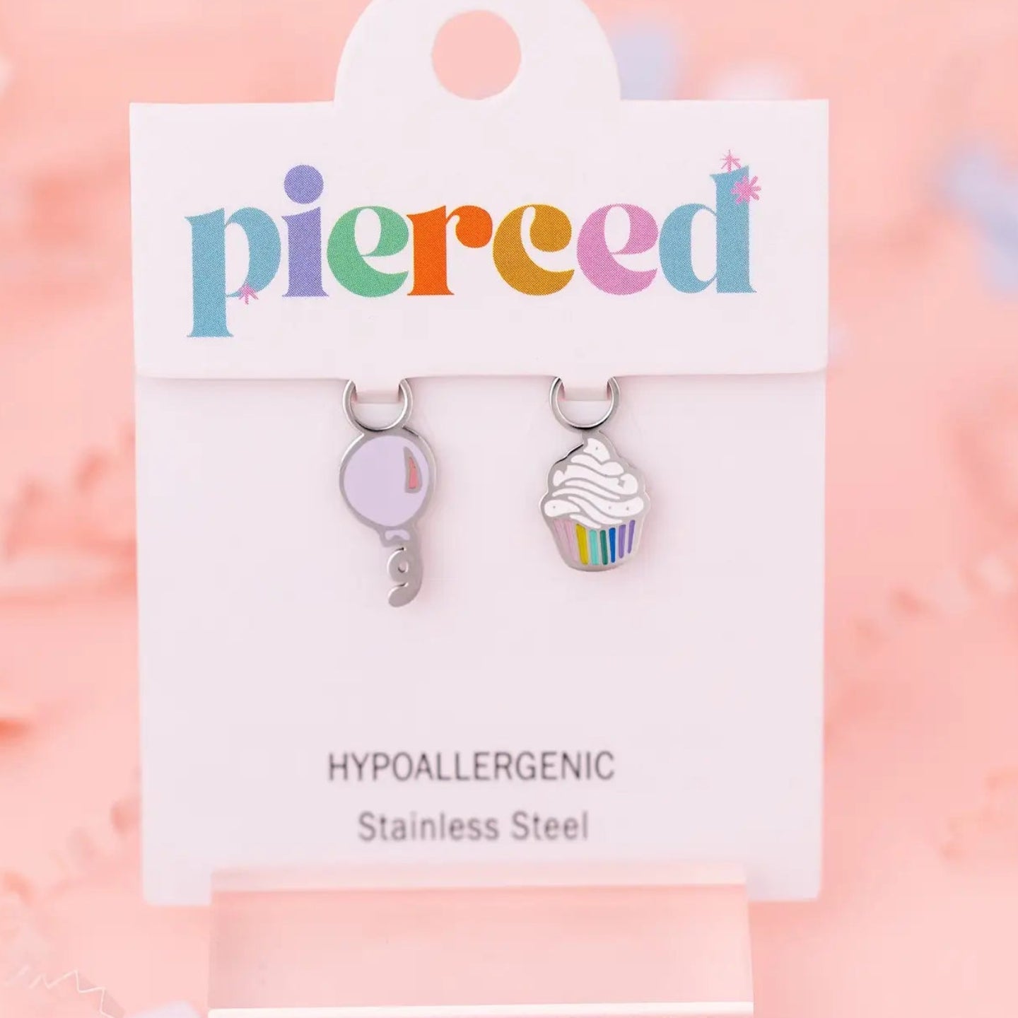 Pair of earrings on a 'pierceed' branded card with a pink background