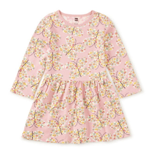 A pink long-sleeve children's dress with a cherry blossom tree print, featuring a gathered waist and a ruffled hem, shown flat on a white background.