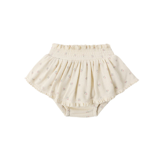 Beige baby bloomers with ruffle details on a white background