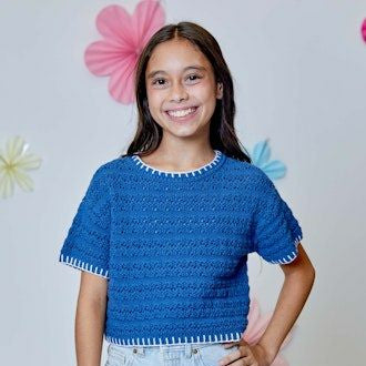 Girl wearing a blue crochet top and denim shorts against a light gray background with decorative elements.