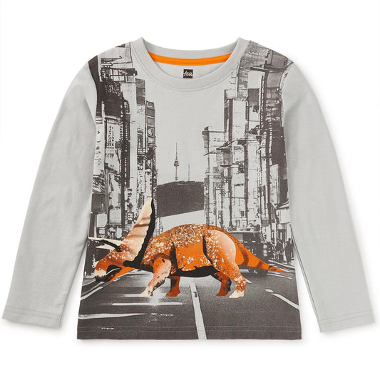 A long sleeve children's t-shirt with a graphic print of a dinosaur on a city street background, predominantly grey in color.