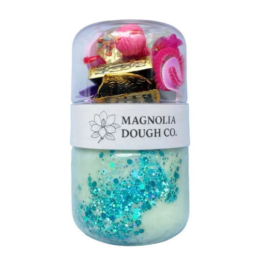 Jar of dough with decorative elements and 'Magnolia Dough Co.' label on a light blue background