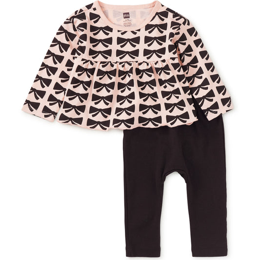 Children's outfit with patterned top and black pants on a white background
